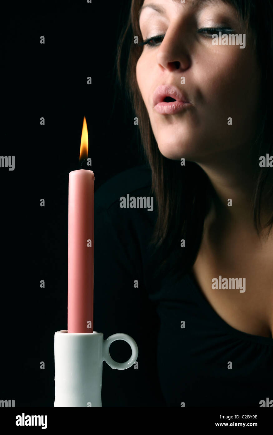 A young woman blowing out a candle Stock Photo Alamy