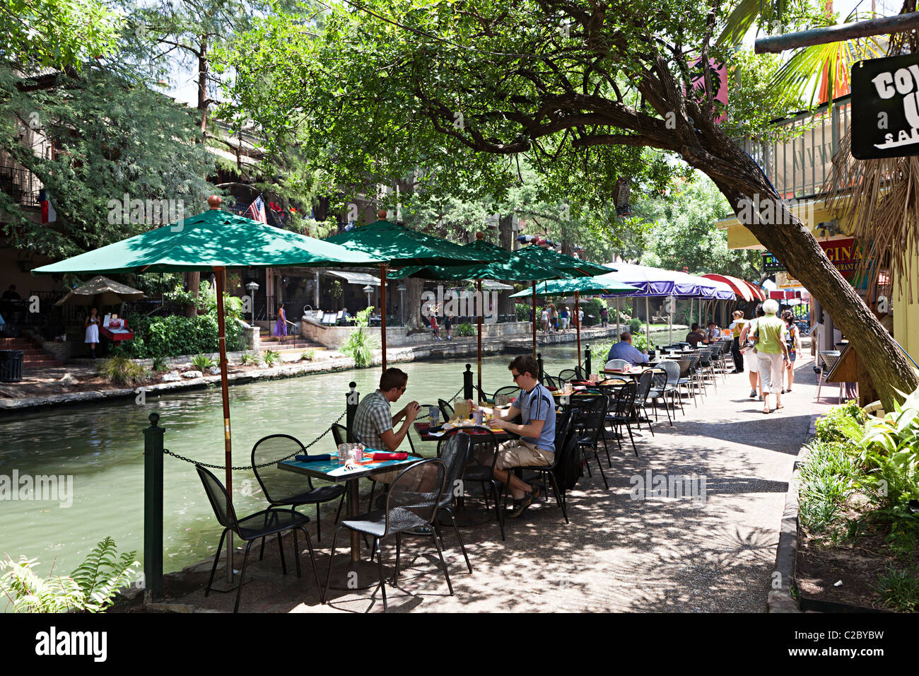 People eating on tables in shade on the Riverwalk San Antonio Texas USA Stock Photo