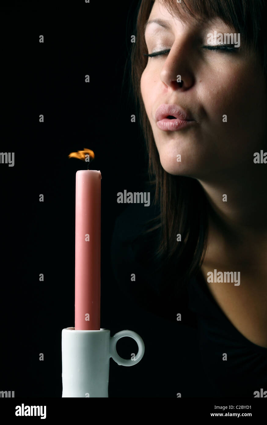 A young woman blowing out a candle Stock Photo Alamy