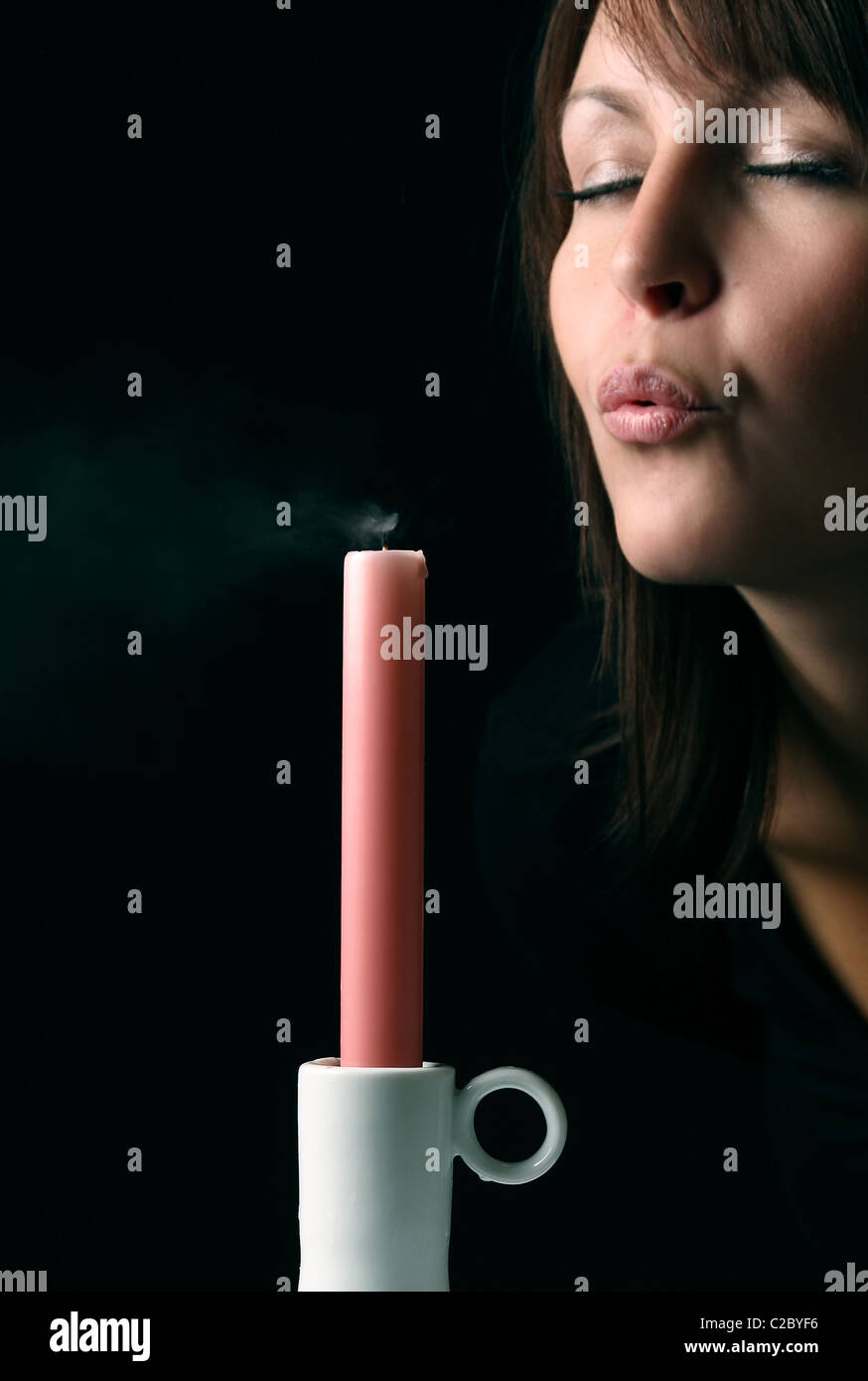 A young woman blowing out a candle Stock Photo Alamy