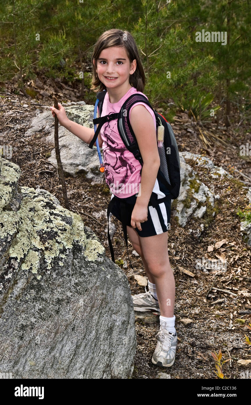 A cute young girl with her backpack of water and hiking stick Stock