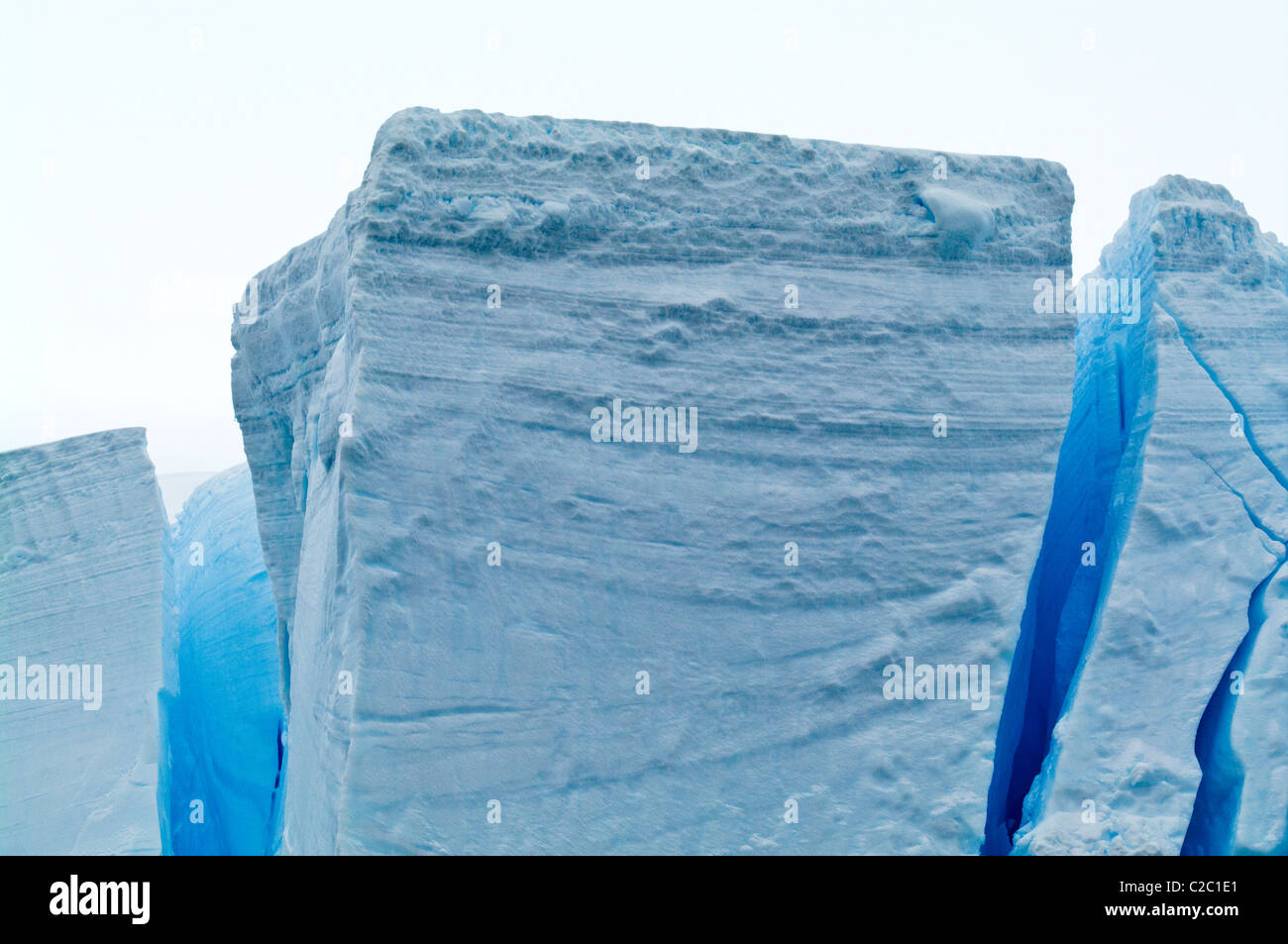 The fracture zone of massive glacial ice cliffs teeter over icy seas. Stock Photo