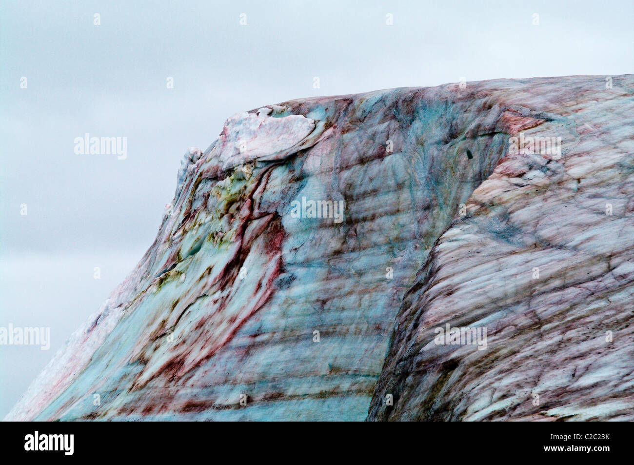 A rugged weathered glacier cap with pink Snow Algae, cryoalgae. Stock Photo