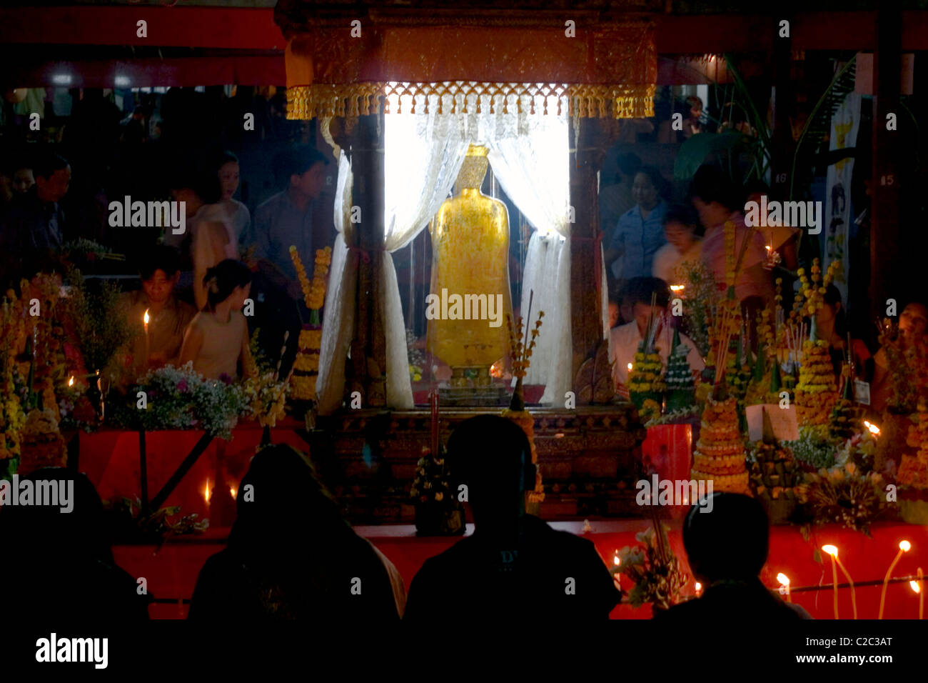 People are gathered with candles to pay tribute to the Pra Bang Buddha at a Buddhist temple in communist Laos. Stock Photo