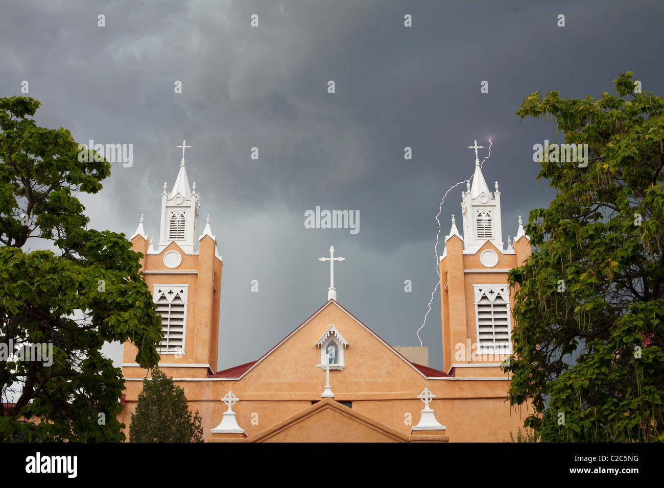 San Felipe de Neri Church in old town Albuquerque. A daylight flash of lightning is striking behind the church. Bernalillo County, New Mexico, USA. Stock Photo