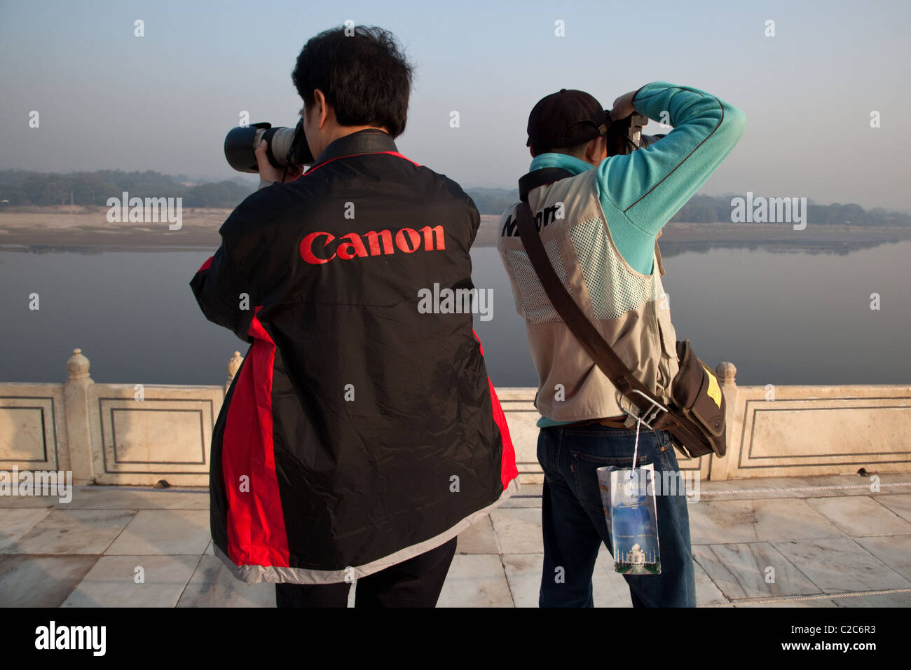 Chinese tourists wearing Canon and Nikon vests take pictures Yamuna river from Taj Mahal in Agra, India. Stock Photo