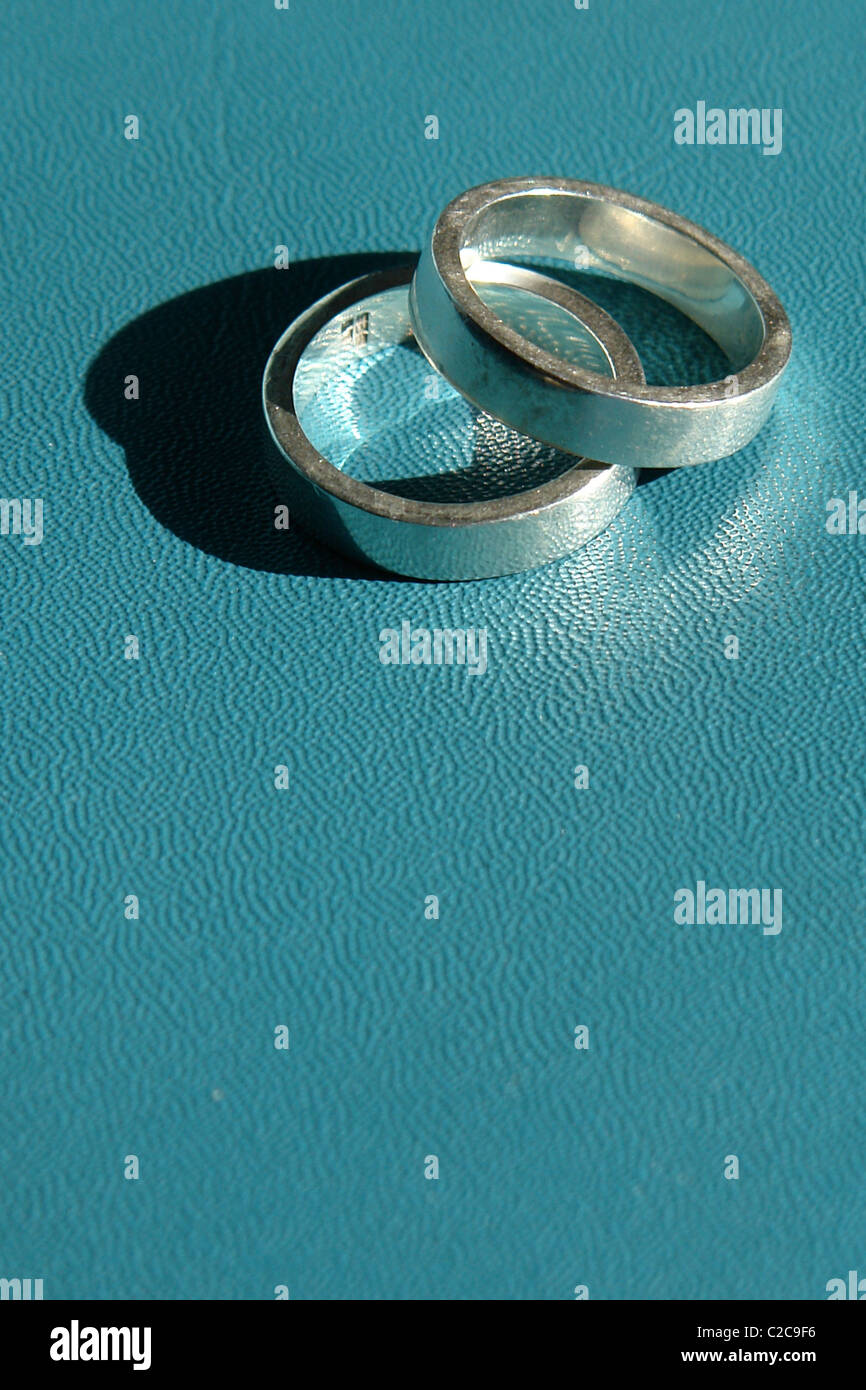 Still Life of Two Silver Wedding Bands on a Turquoise Blue Background