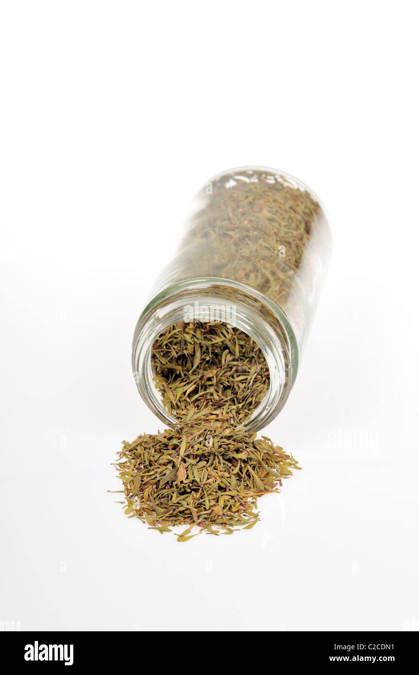 Dried Thyme herb spilled out of bottle on side on white background
