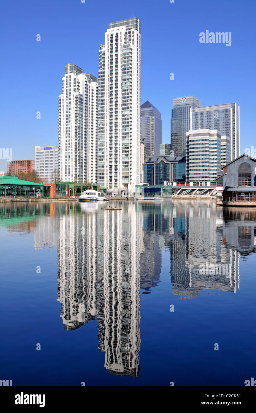 East London Docklands waterside high rise apartment flats development reflections old Inner Millwall Dock Canary Wharf office tower block beyond UK Stock Photo