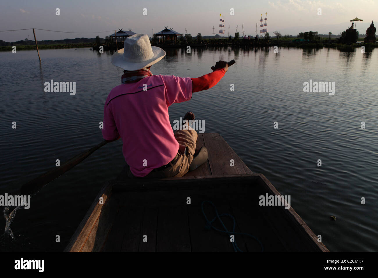 A man paddles towards a Buddhist temple in Phayao, Thailand. Stock Photo