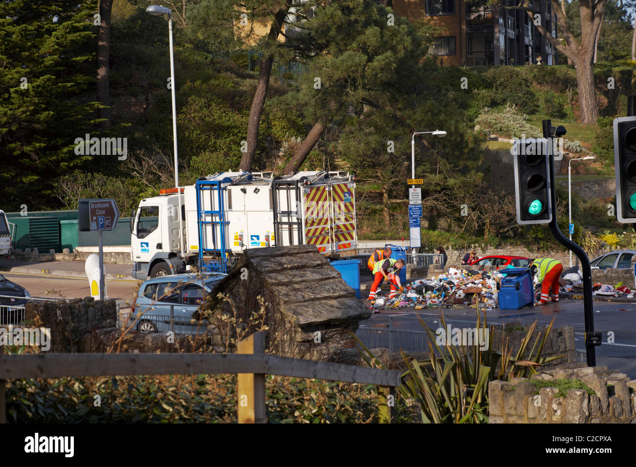 Council workers clearing up piles of rubbish in road with wheelie bins upturned following an incident at Branksome Chine, April Stock Photo
