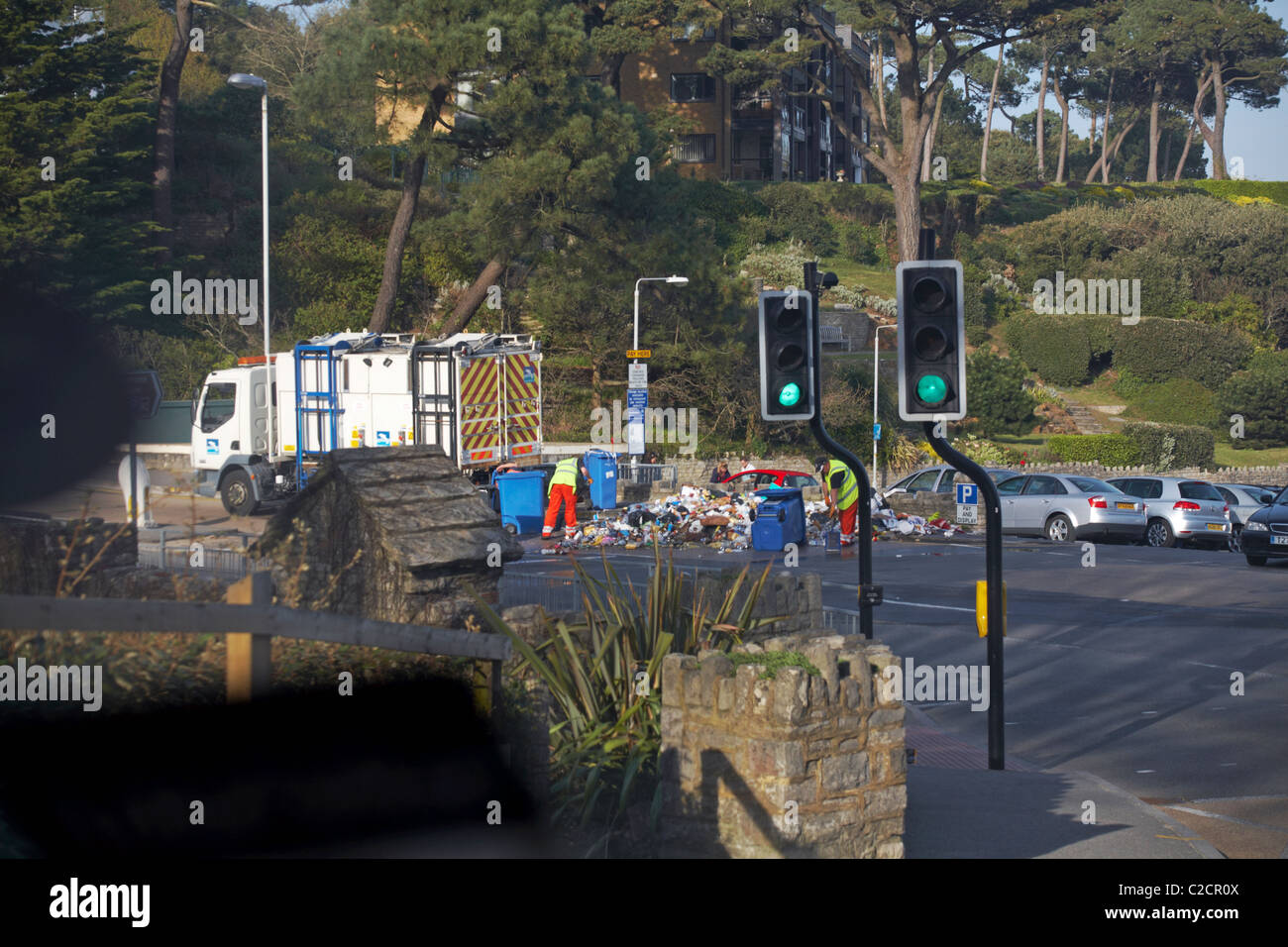 Council workers clearing up piles of rubbish in road with wheelie bins upturned at Branksome Chine in April Stock Photo