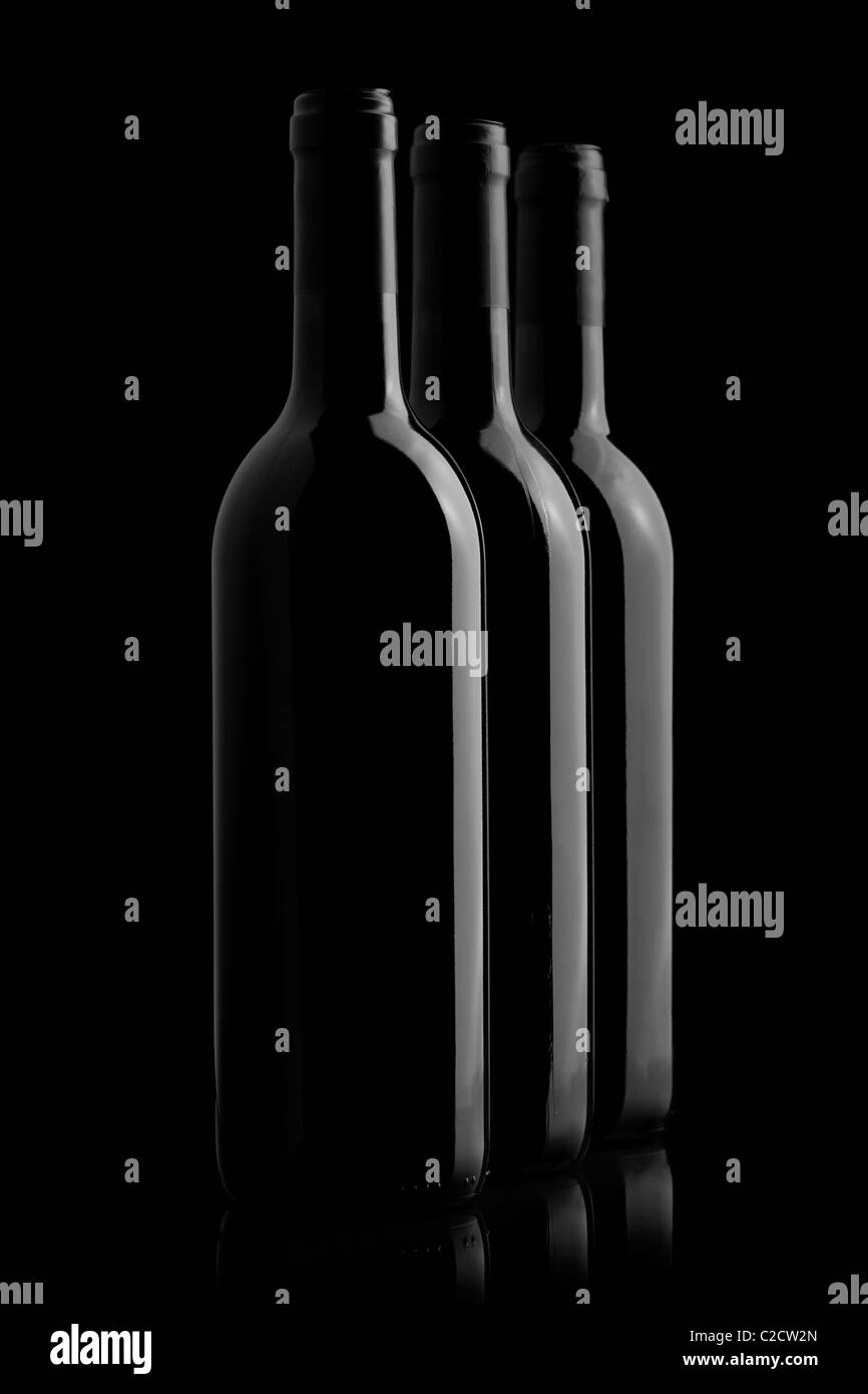 Three elegant wine bottles in a black background Stock Photo
