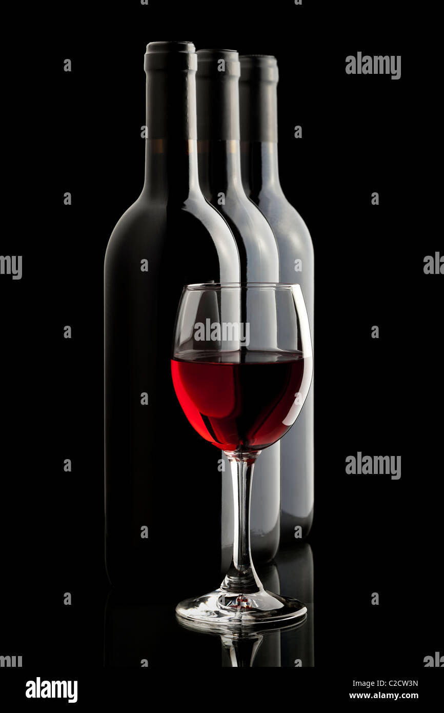 Elegant red wine glass and a wine bottles in black background Stock Photo