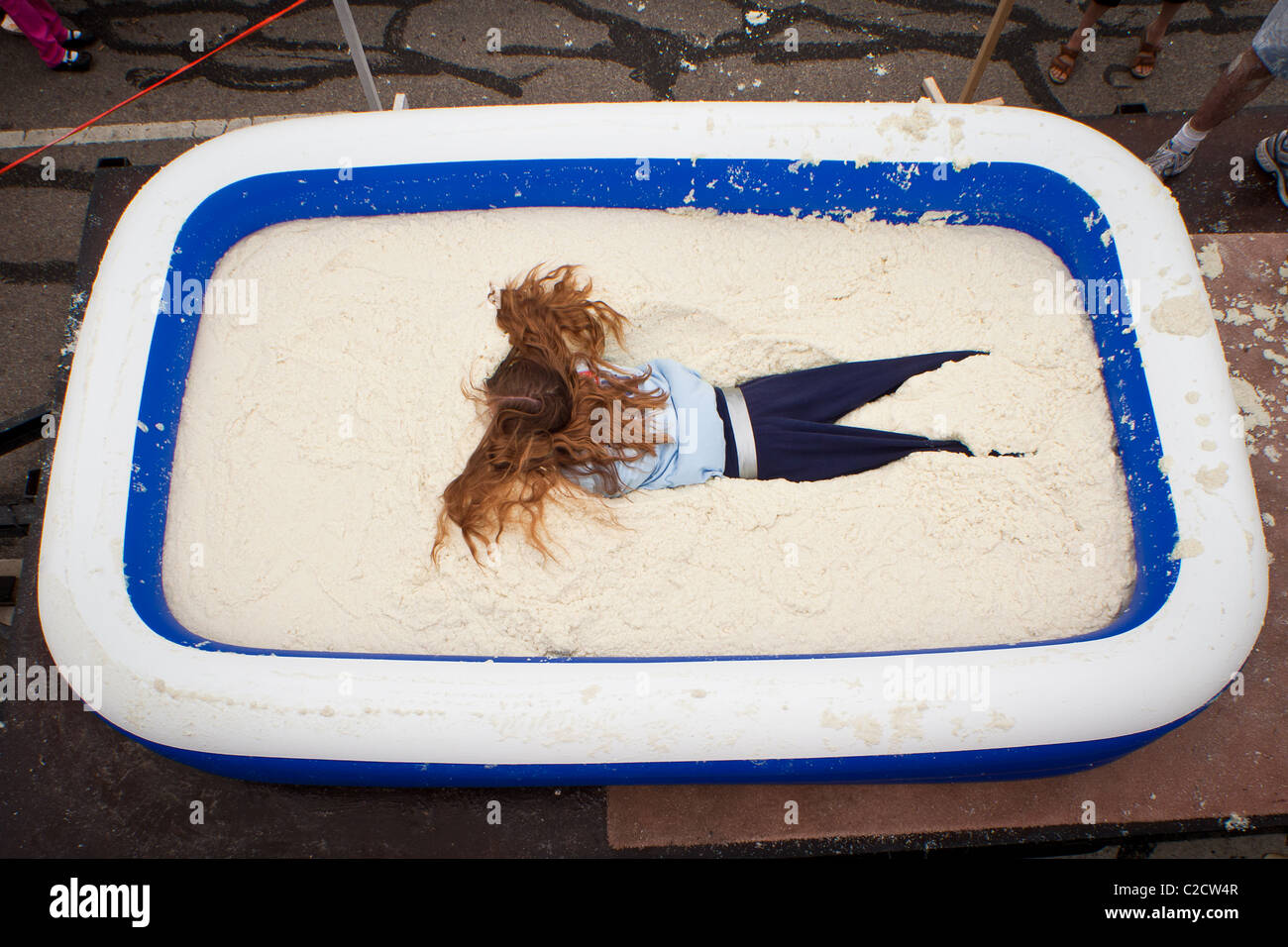 A participant in the Grits Roll wallows in a pool of grits during the annual World Grits Festival in St George, SC Stock Photo
