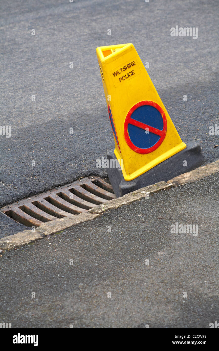 Wiltshire Police no parking cone by side of drain cover in road Stock Photo