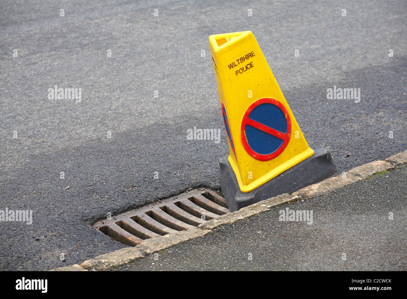 Wiltshire Police no parking cone by side of drain cover in road Stock Photo