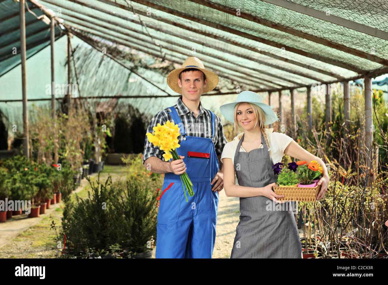 Male and female gardeners holding pots in a garden Stock Photo - Alamy