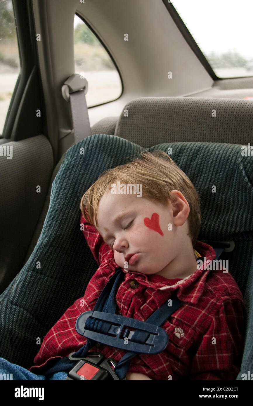 A 3 year old boy sleeping in his car seat during nap time.after a