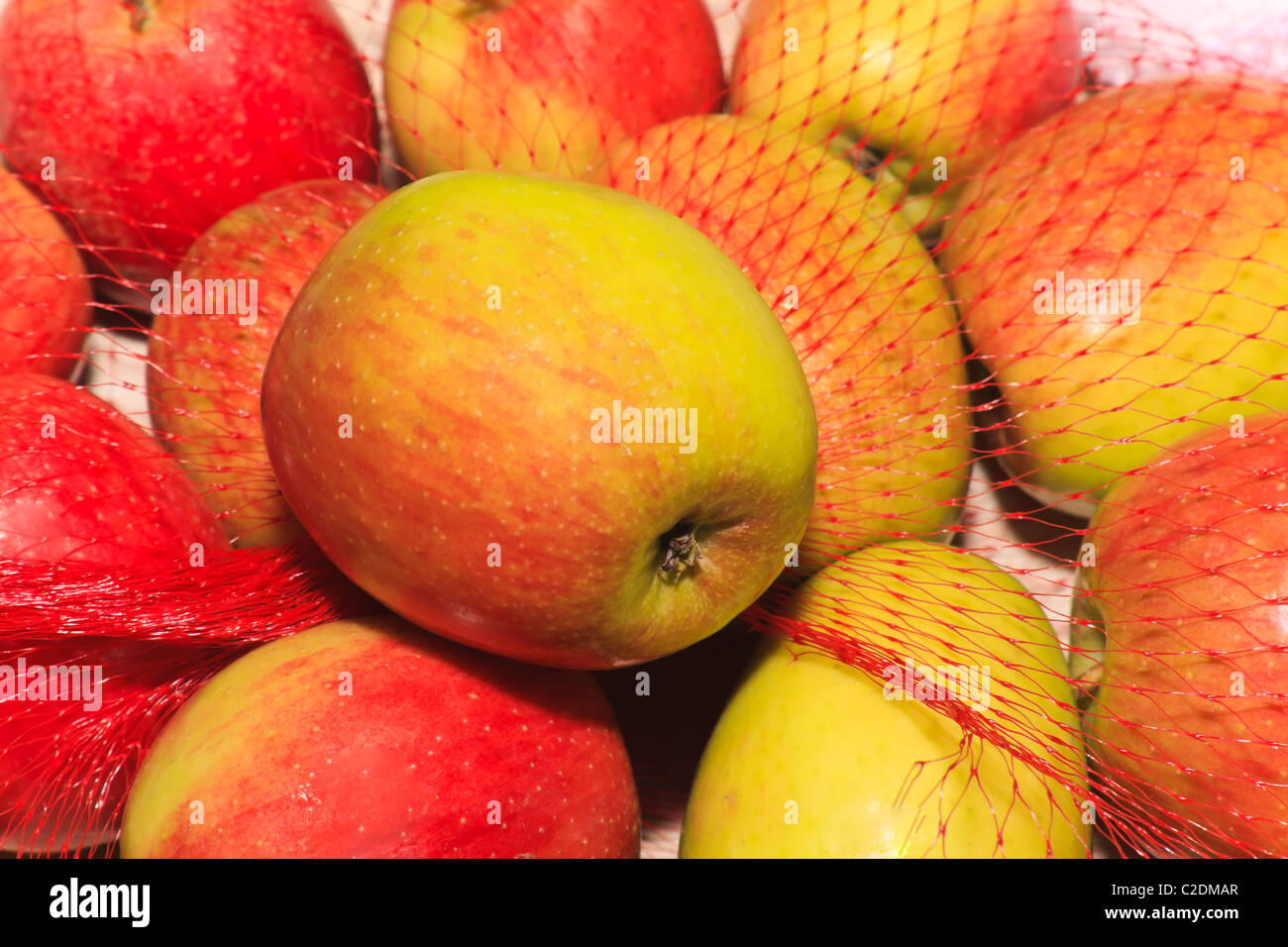 Red and yellow ripe apples in net Stock Photo