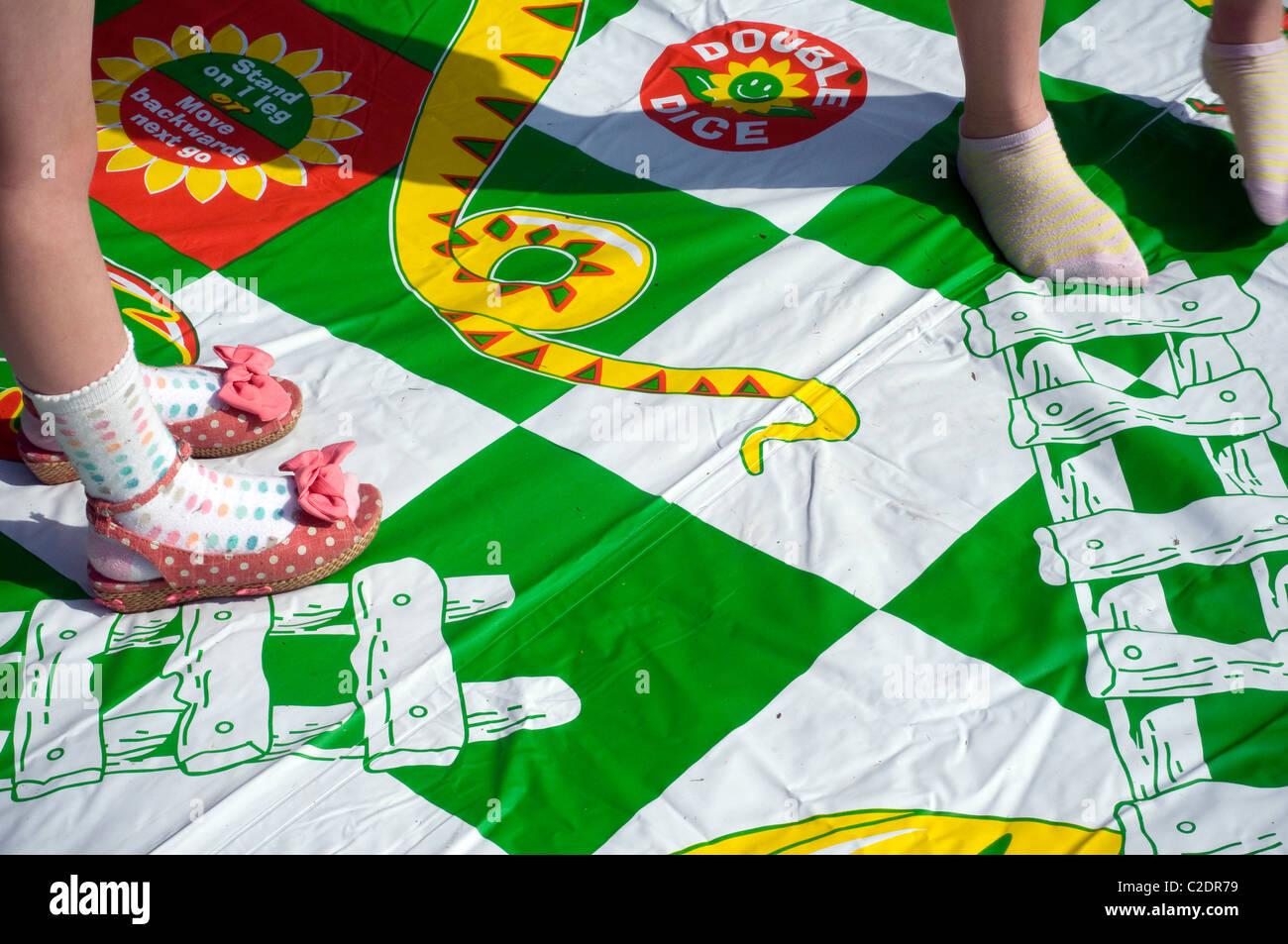 Childrens feet as they play Giant Snakes & Ladders to encourage numeracy and visual skills Snakes and Ladder,repose, rest, ease, Stock Photo