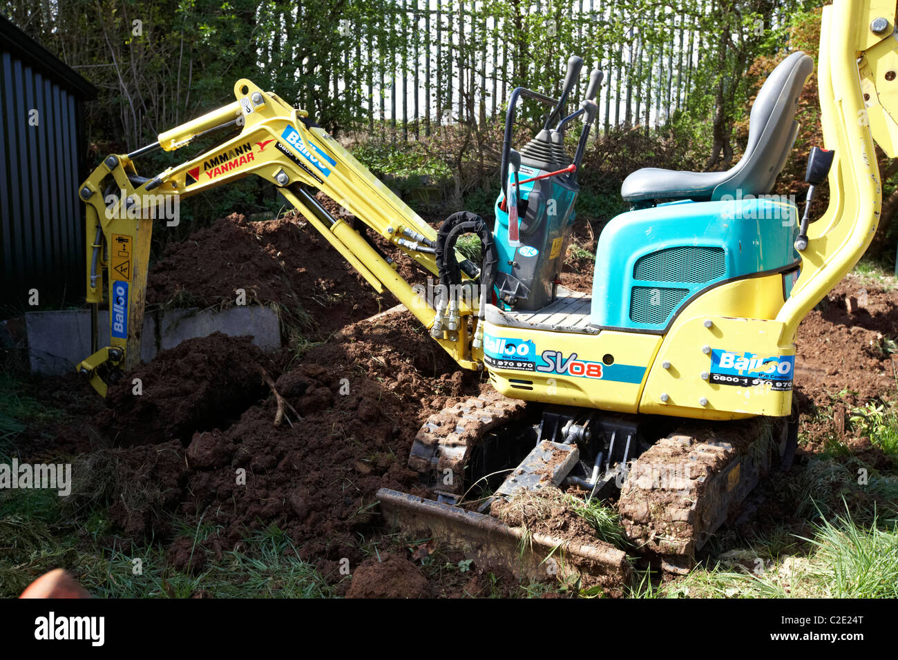 hired mini micro digger excavating small garden in the uk Stock Photo