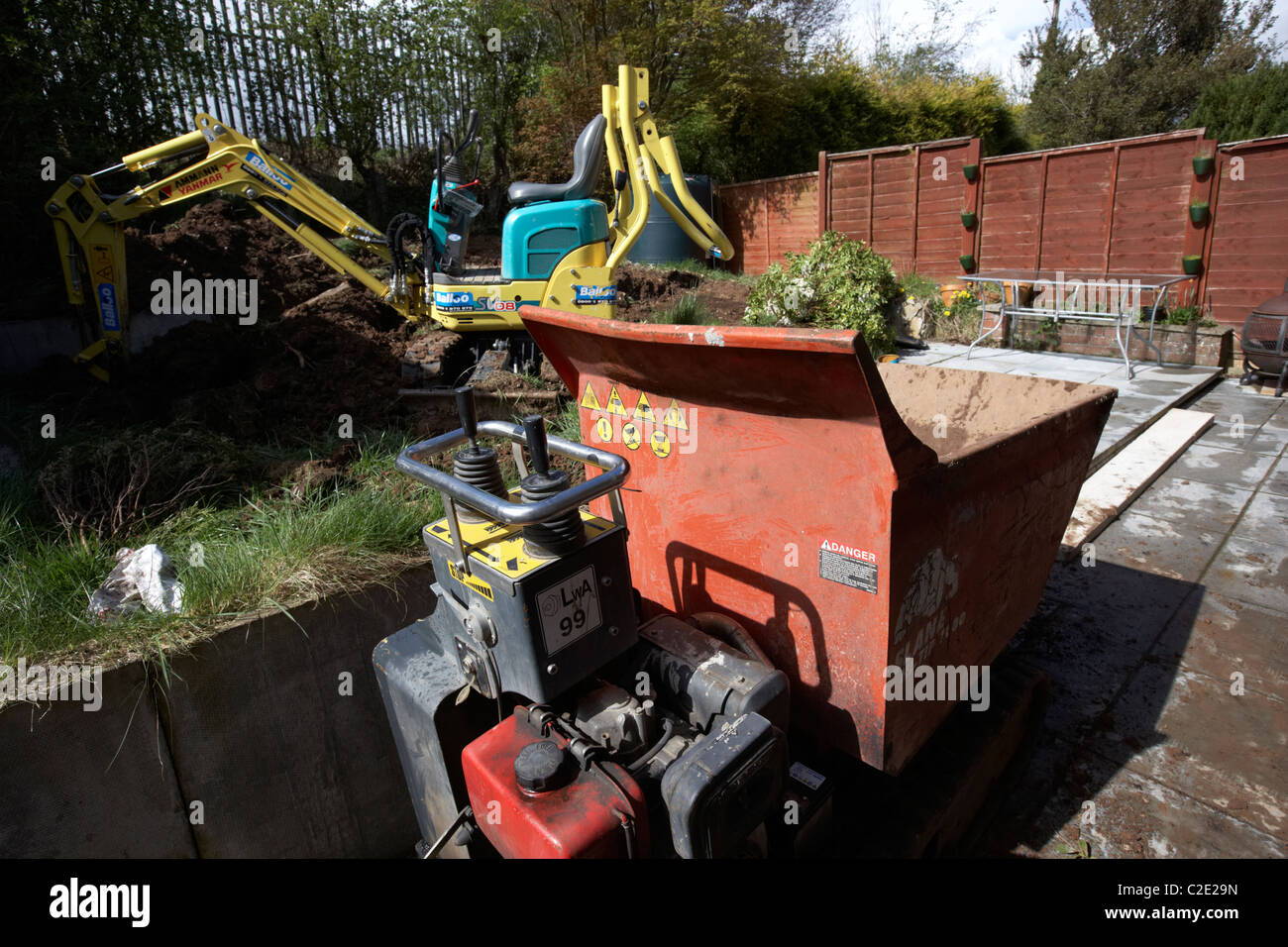 hired hi-tip dumper and micro digger excavating small garden in the uk Stock Photo