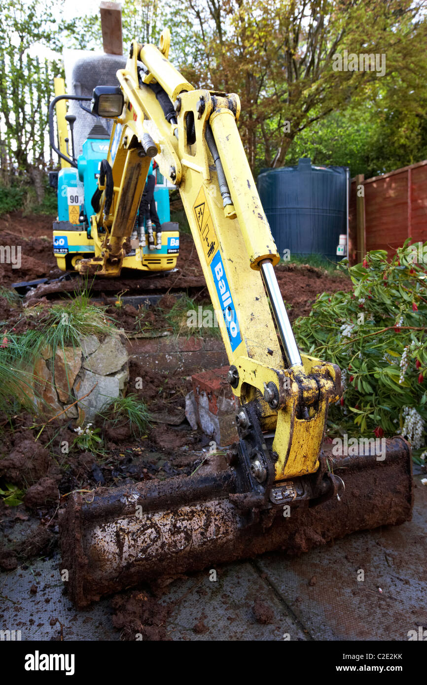 hired mini micro digger excavating small garden in the uk Stock Photo