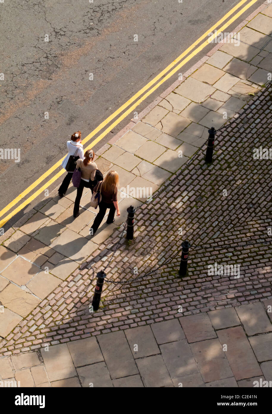 View looking down on three pedestrians walking down a street in the UK Stock Photo