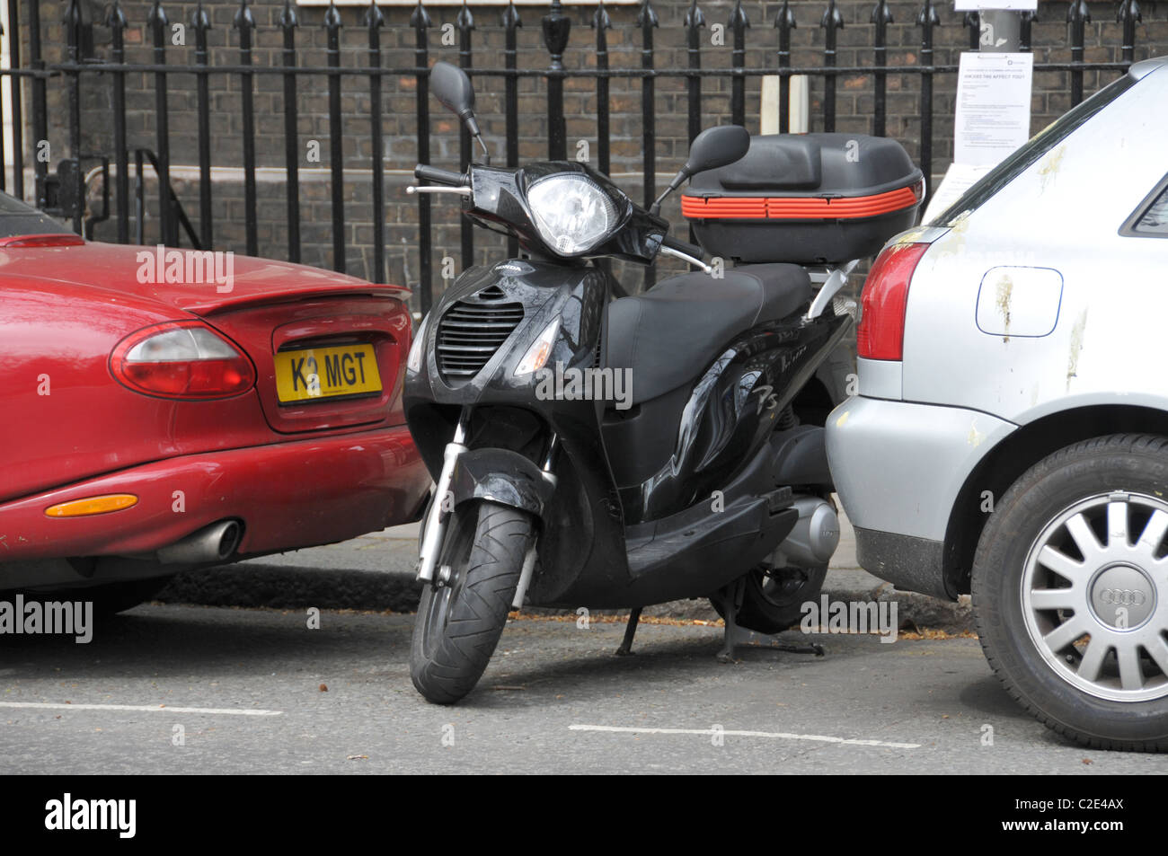 Scooter parked small gap cars parking space tight squeeze small economical travel commuting Stock Photo