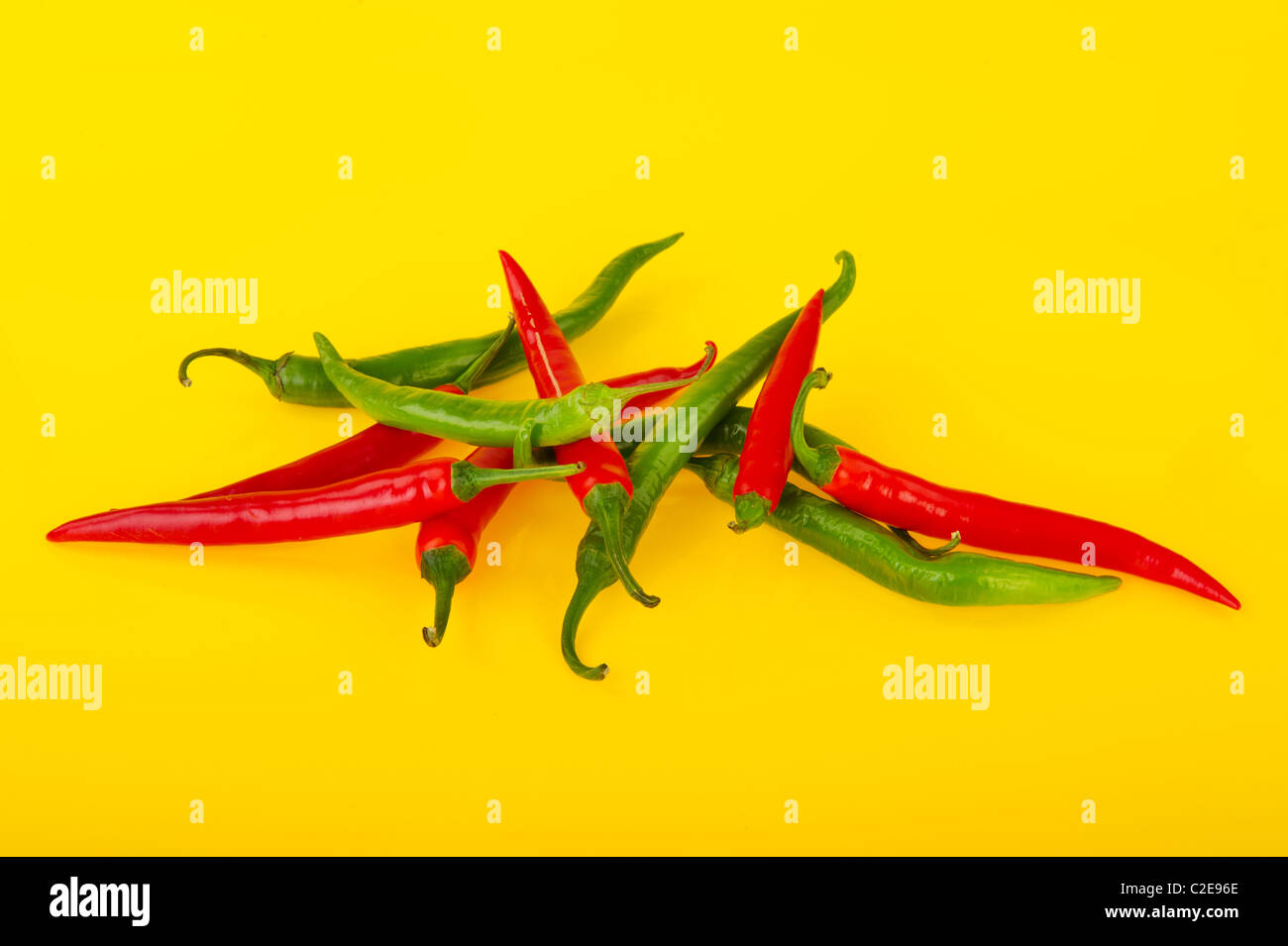 Fresh red and green chili peppers on yellow background Stock Photo - Alamy