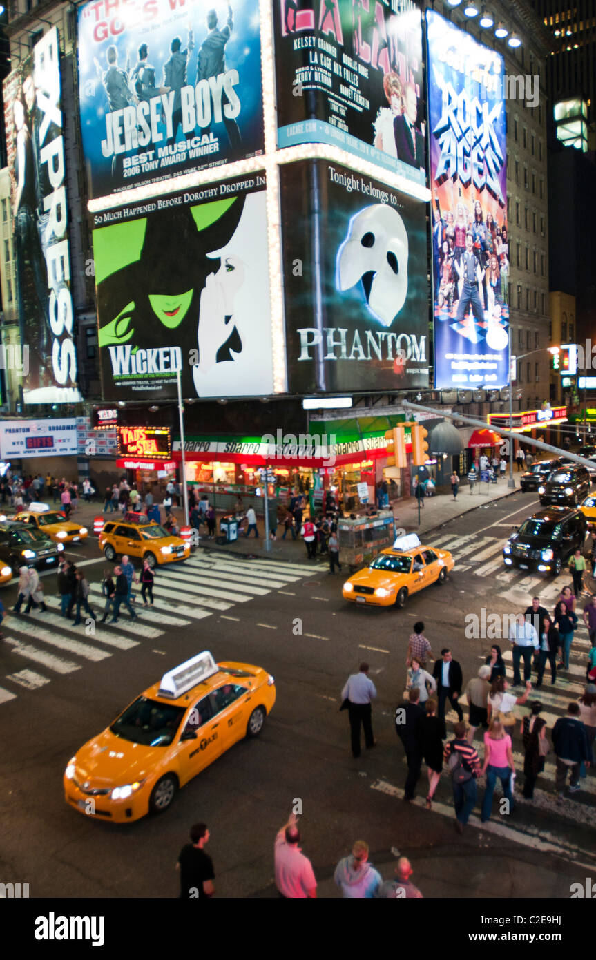 Night scene yellow taxi cabs and tourist crossing West 47th Street and 7th Avenue with Sbarro pizzeria and Phantom Times Square Stock Photo