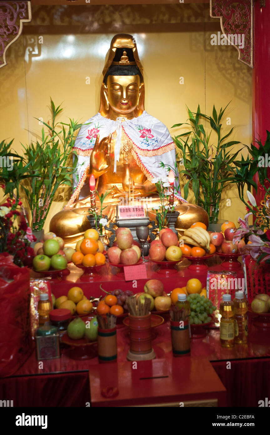 Gold Buddha statue with fruits offering at Mahayana Buddhist Temple, Chinatown, Manhattan, New York City, USA Stock Photo