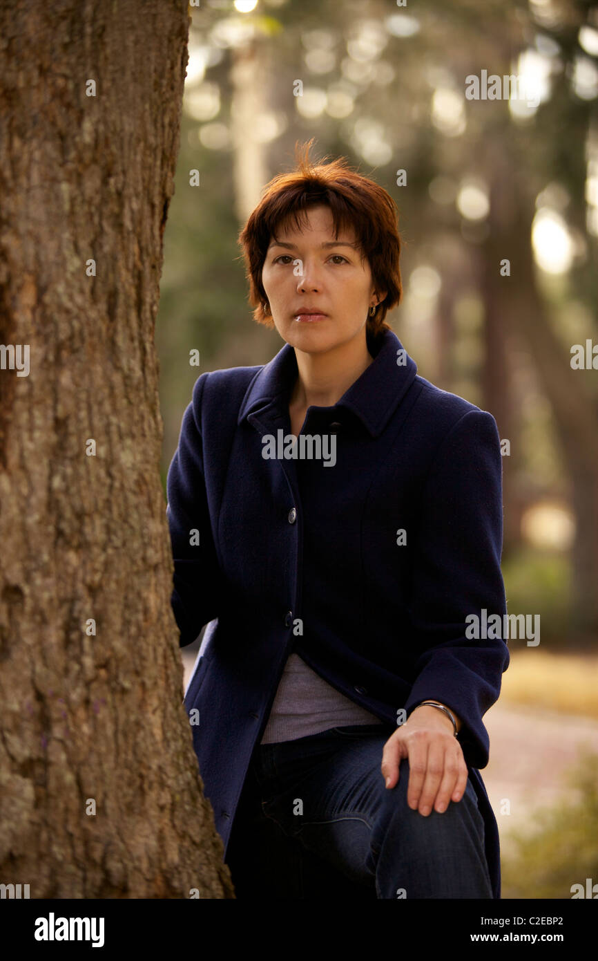 A beautiful young woman poses by a tree in a park Stock Photo - Alamy