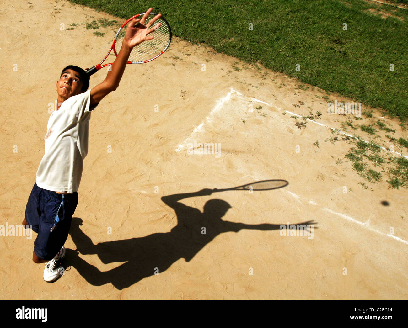 Tennis Player going for a big service on the clay court in Chandigarh, India Stock Photo
