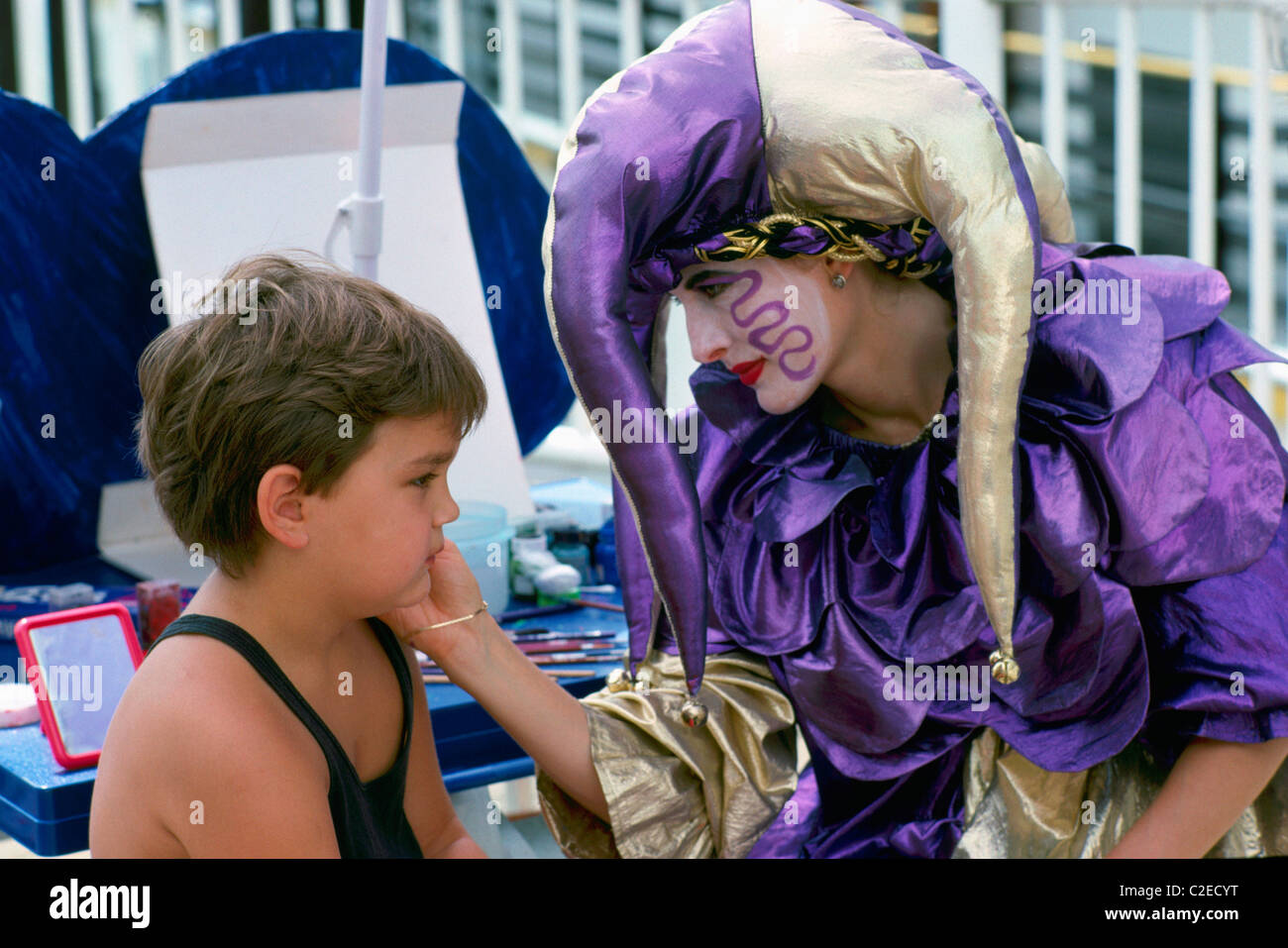 Face Painting - Clown paints Face of Young Boy Child Stock Photo