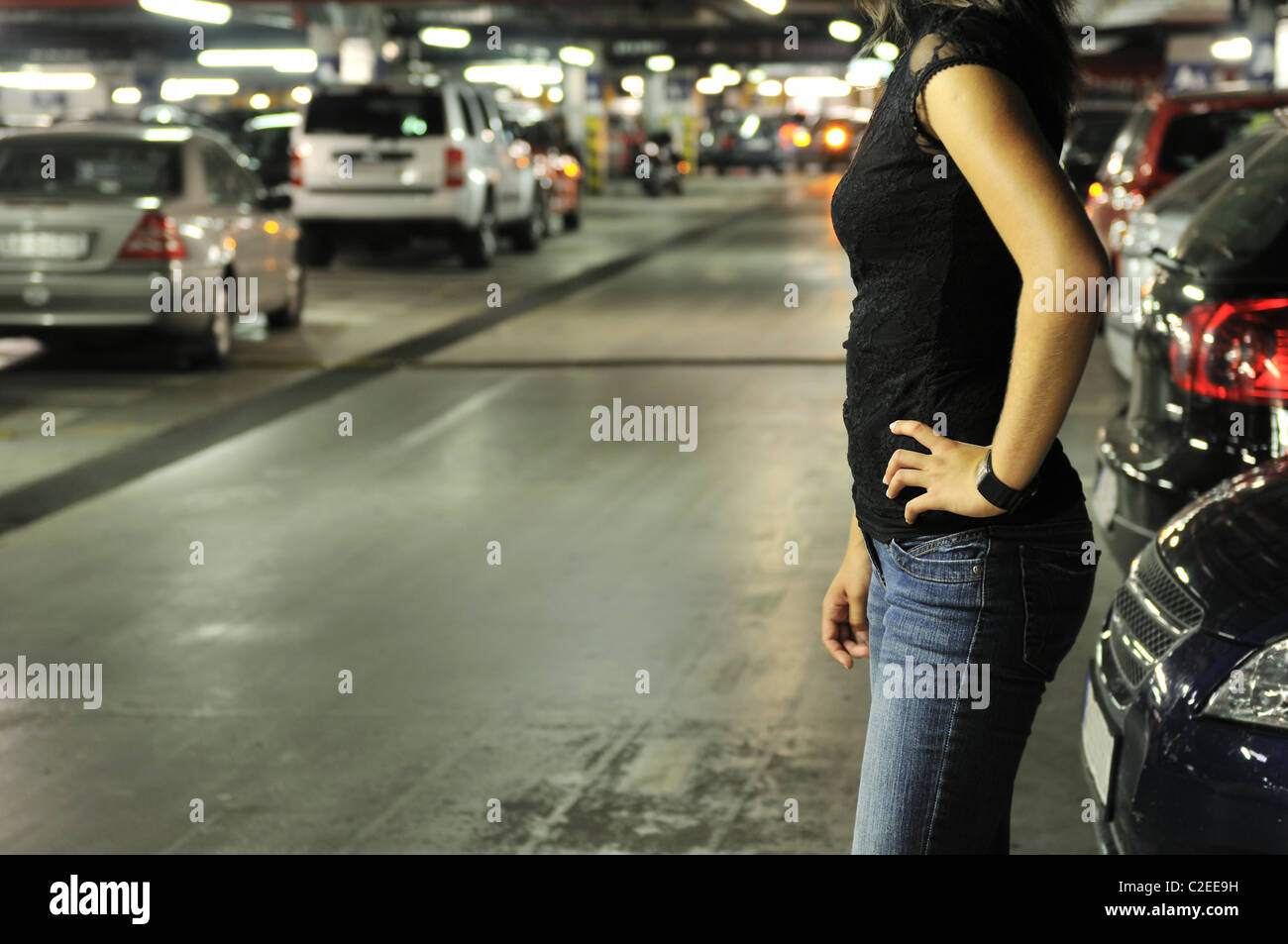 Young woman standing at car in underground parking place Stock Photo