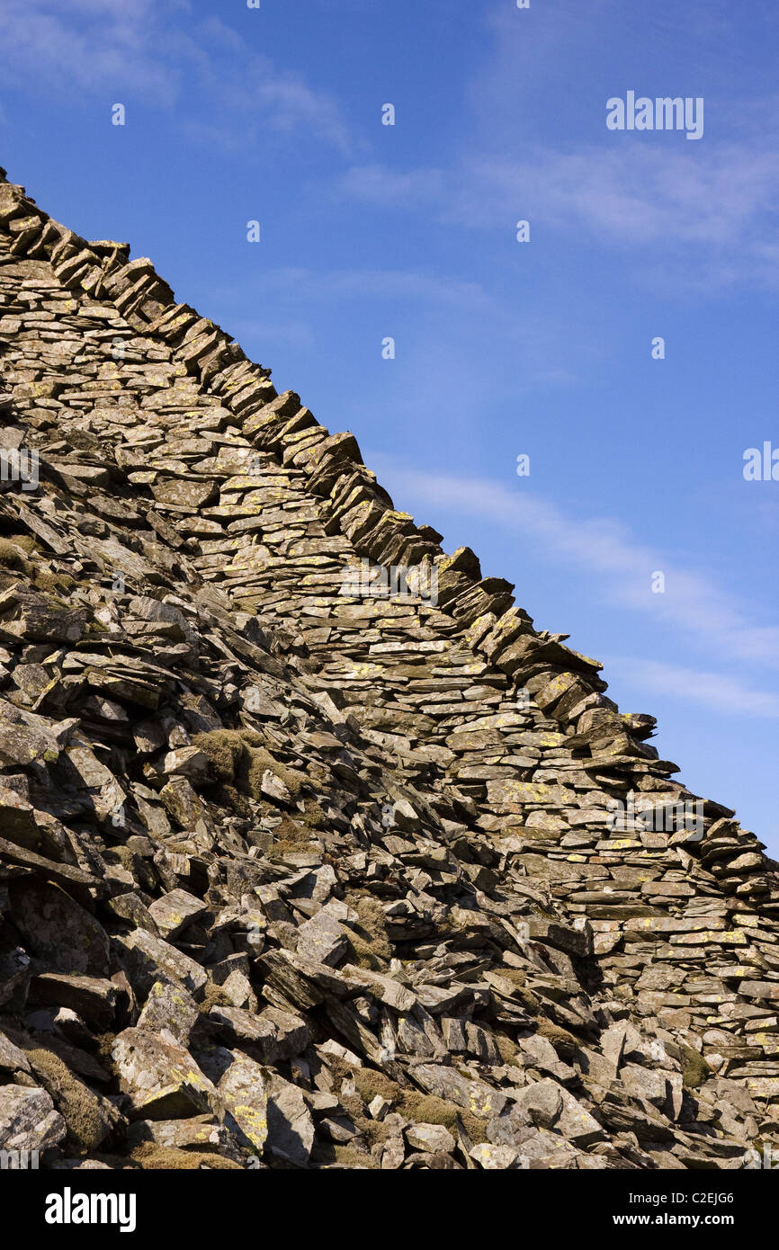 Old slate dry stone wall on very steep hillside on Lingmoor Fell with blue sky behind, Lake District, Cumbria, England, UK Stock Photo