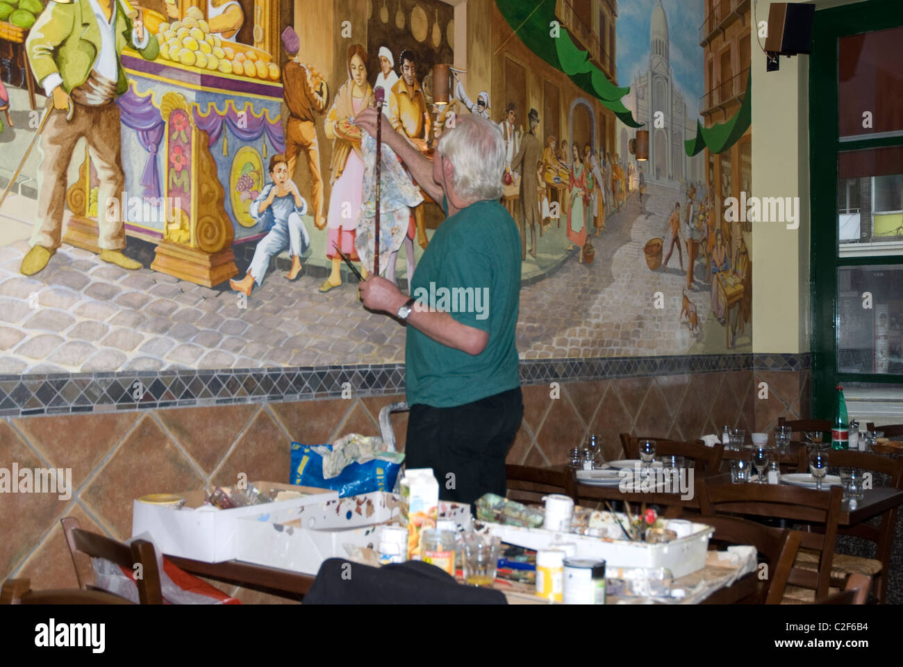 Artist painting mural on the wall of an Italian restaurant Notting Hill