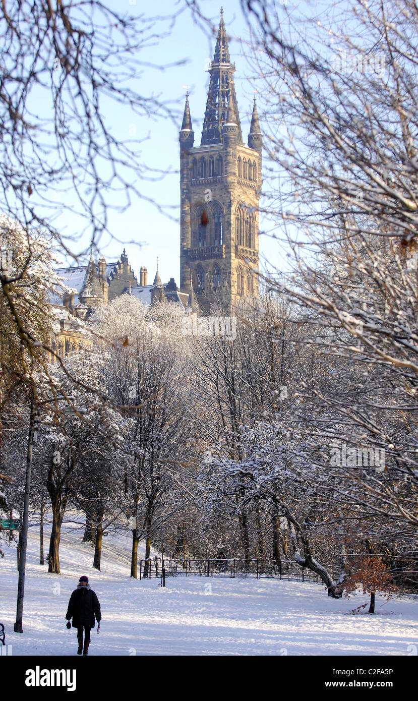 A person walks through Kelvingrove park in Glasgow after a heavy snowfall. The University of Glasgow is pictured behind. Stock Photo