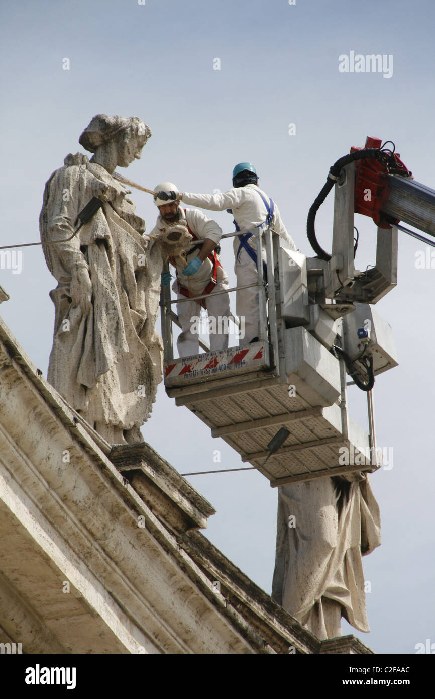 workers repairing statues on top of colonnade at st peter's square in