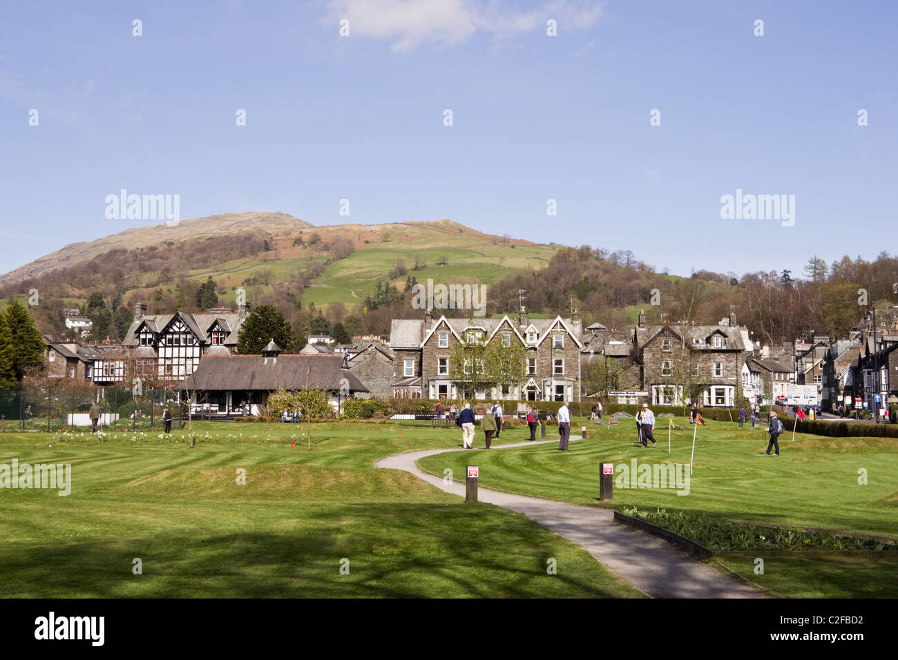 View of Cumbrian town with path across the park putting green. Ambleside, Cumbria, England, UK, Britain. Stock Photo