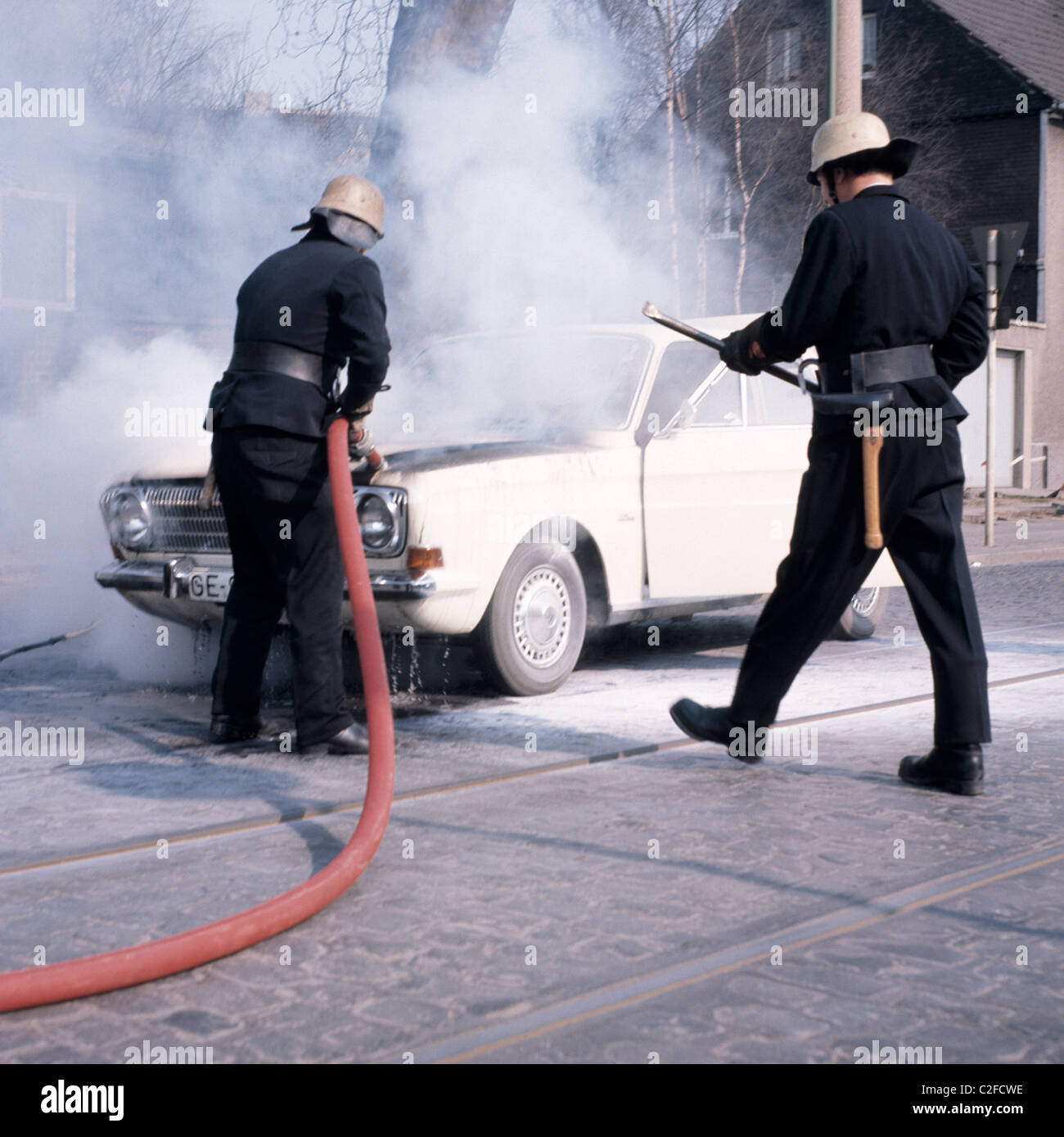 Seventies, road traffic, accident, fire brigade operation, firemen extinguish a burning car, D-Gelsenkirchen, Ruhr area, North Rhine-Westphalia, NRW, D-Gelsenkirchen-Buer Stock Photo