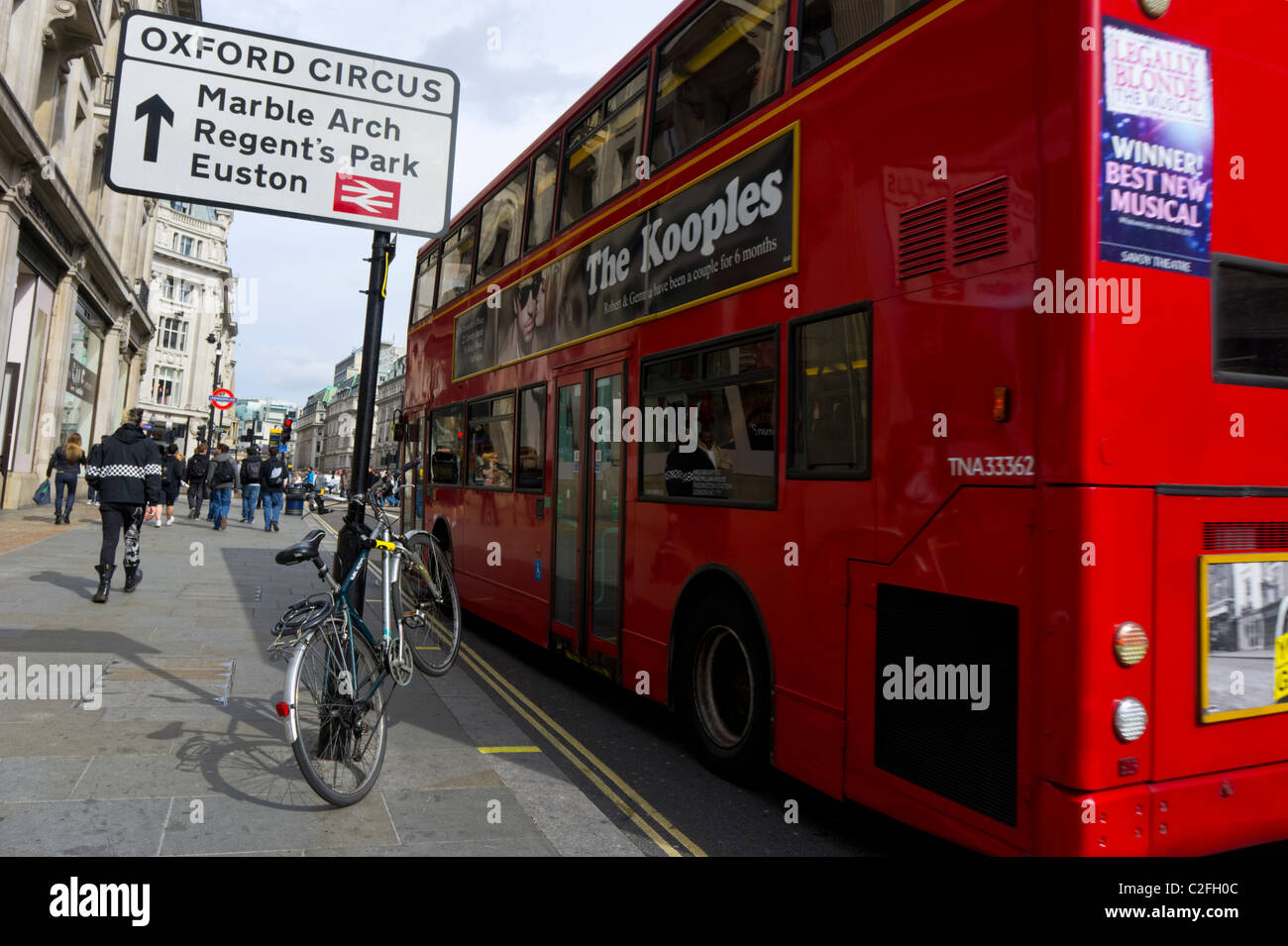 Bus stops next to a bicycle chained to a London street sign post Stock Photo