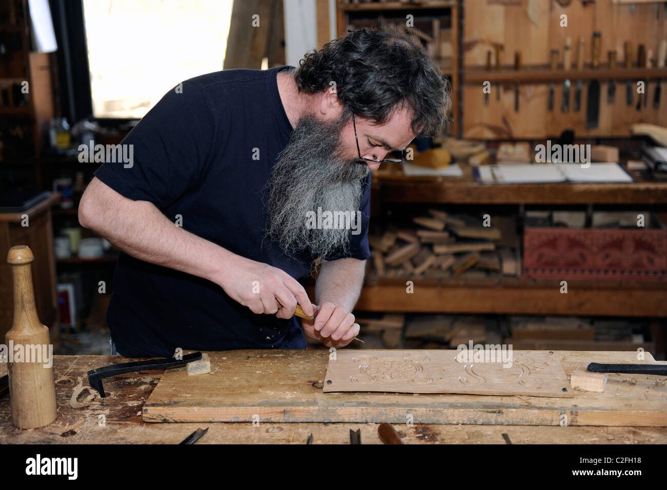 Craftsman shows free hand carving technique to make English furniture at Plimouth Plantation. Stock Photo