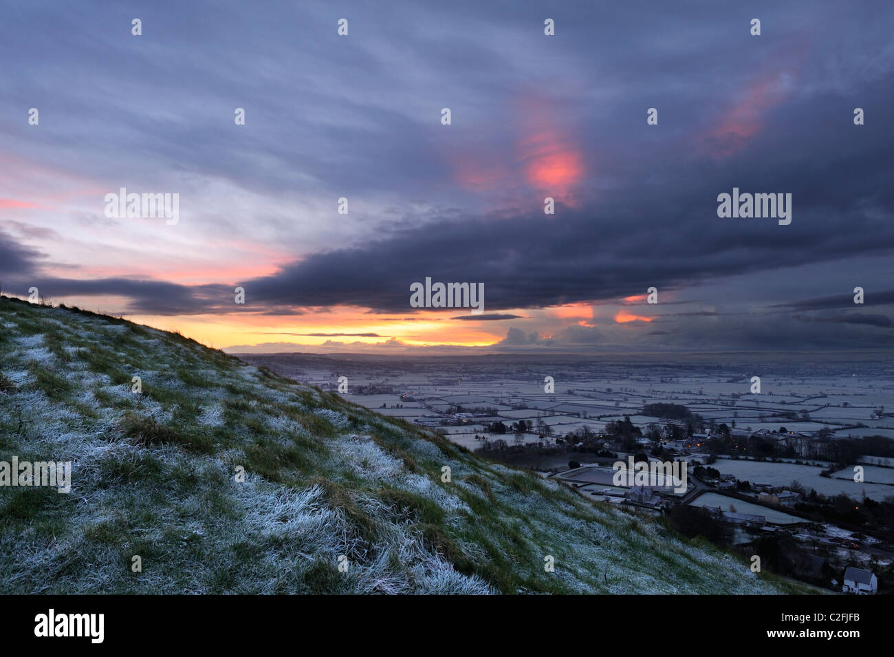 The winter morning sun breaking through thick clouds over the Somerset Levels near Glastonbury, Somerset Stock Photo