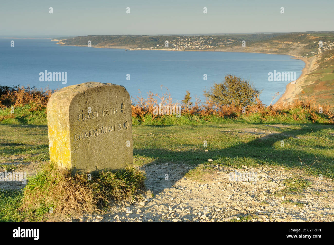 A stone signpost on the South West Coastal Path pointing towards Charmouth, Dorset. Stock Photo