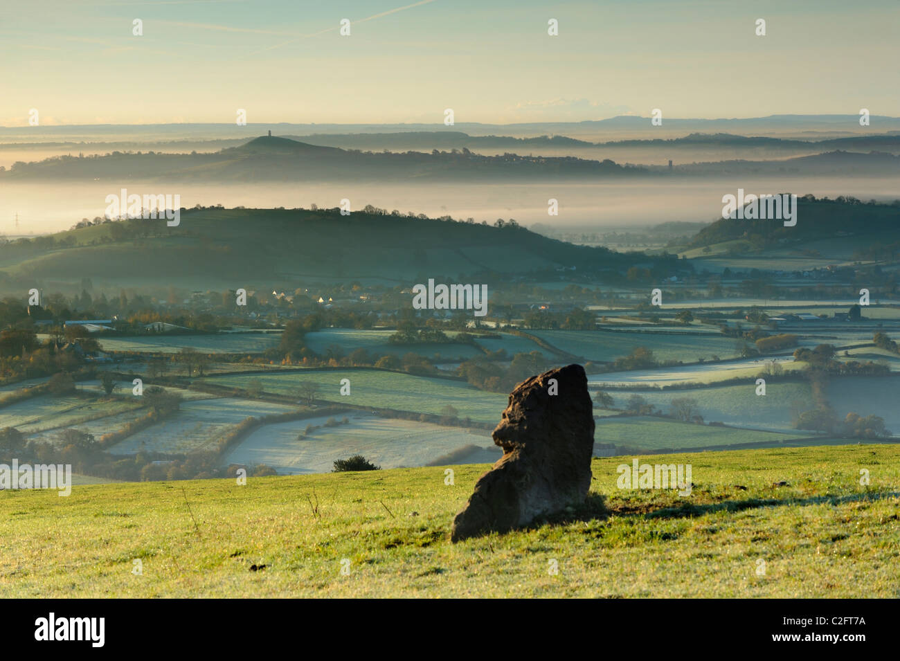 An ancient standing stone on the Mendip Hills overlooking a mist scene on the Somerset Levels. Stock Photo