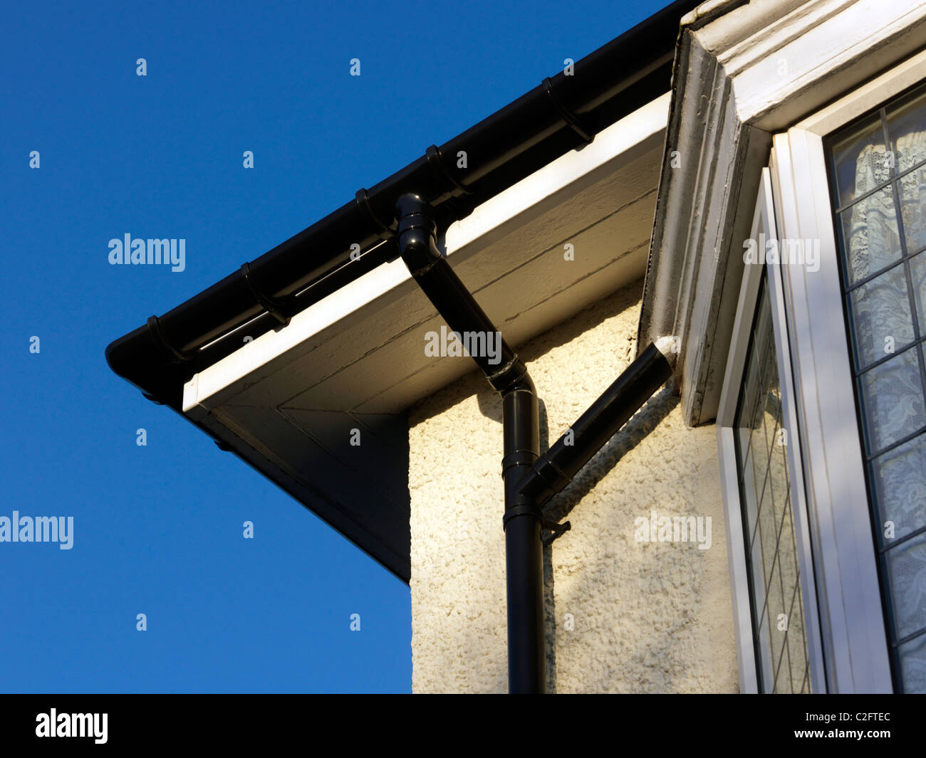 Gutter, Support Brackets, Offset Bend And Downpipe On The Side Of A House Stock Photo
