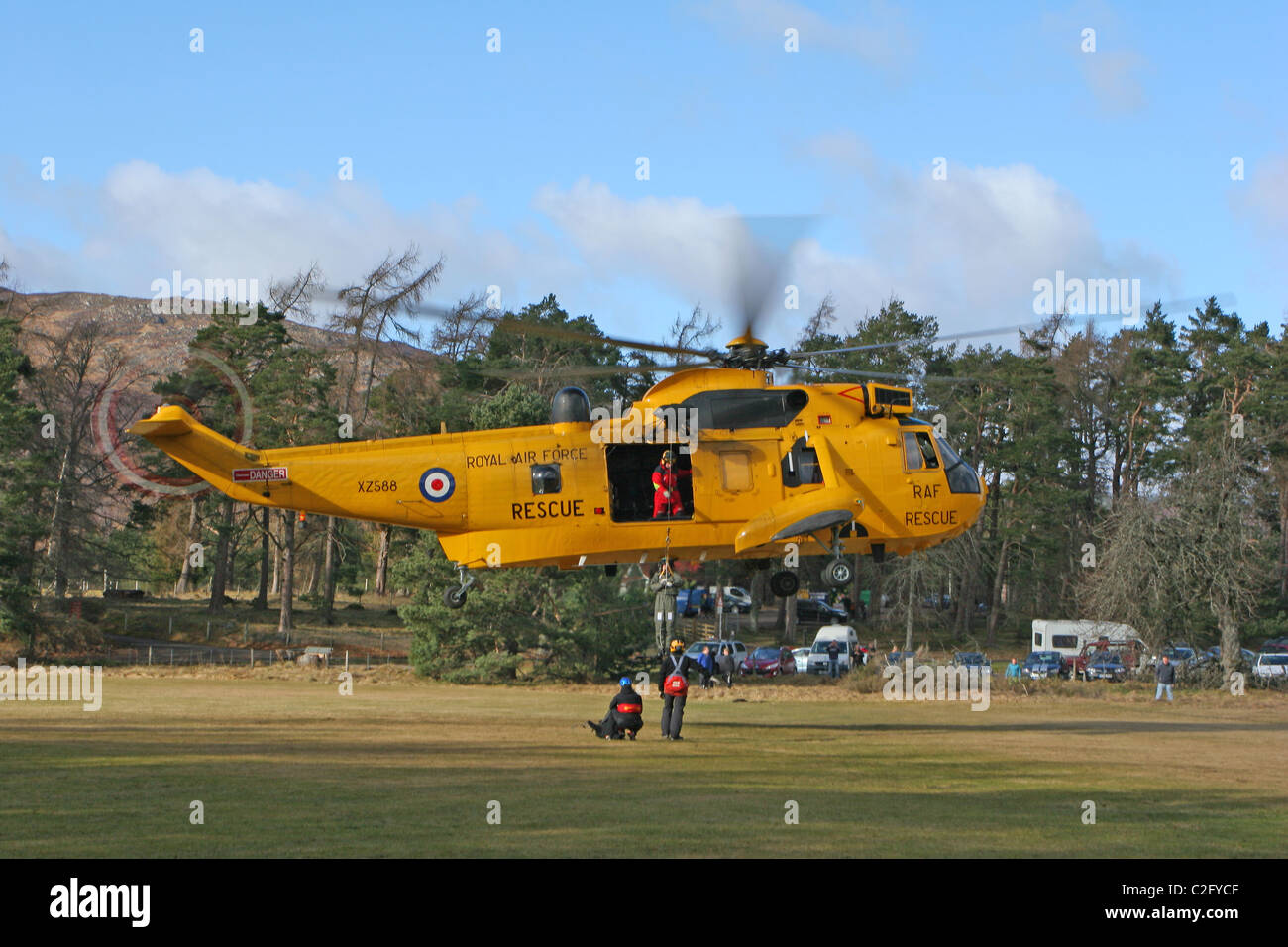 RAF Sea King SAR helicopter hovering and winching a crew member aboard at Rothiemurchus near Aviemore. Stock Photo